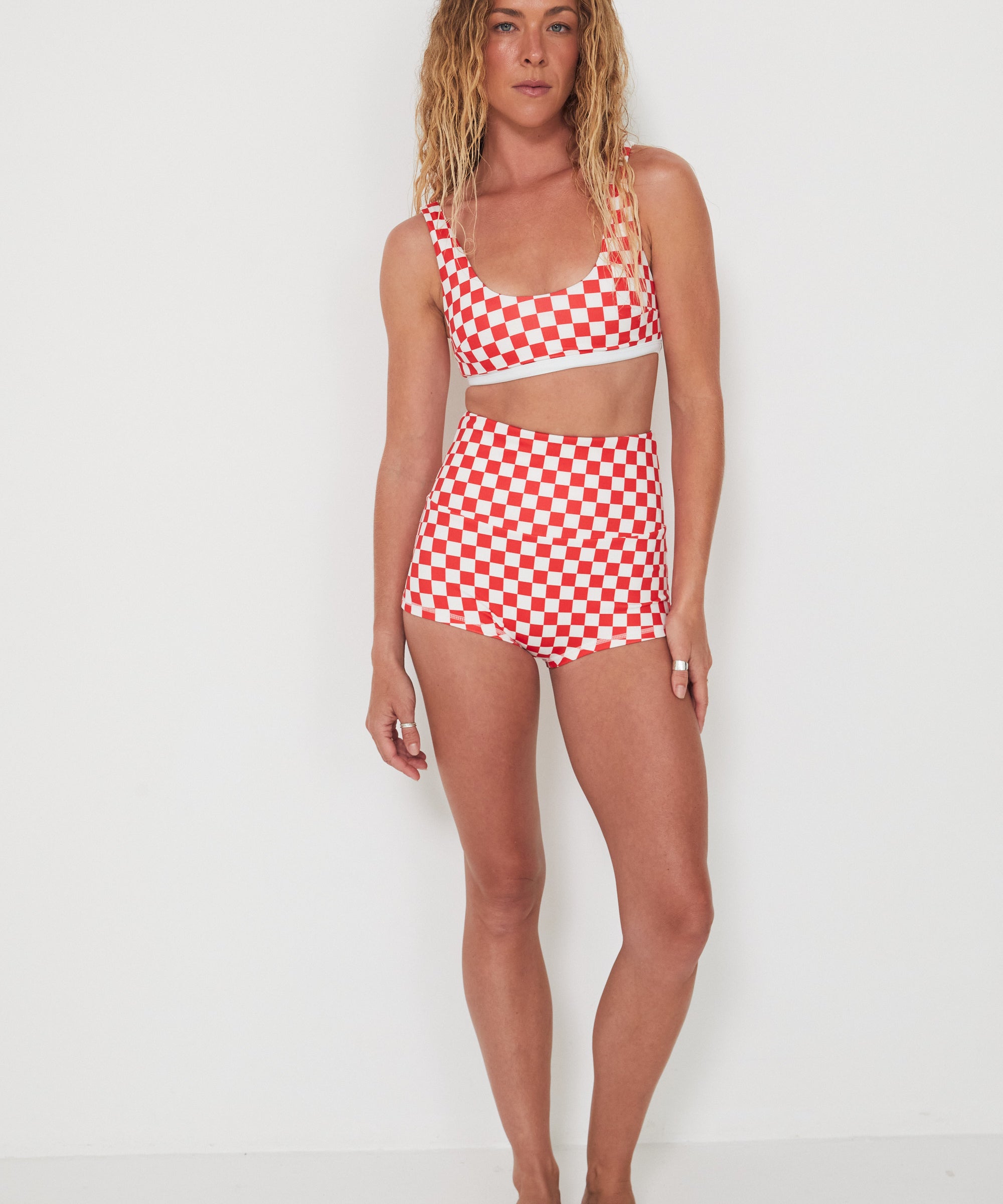 Woman wearing a red and white checkered bralette swim top and original betty bottoms on a white background