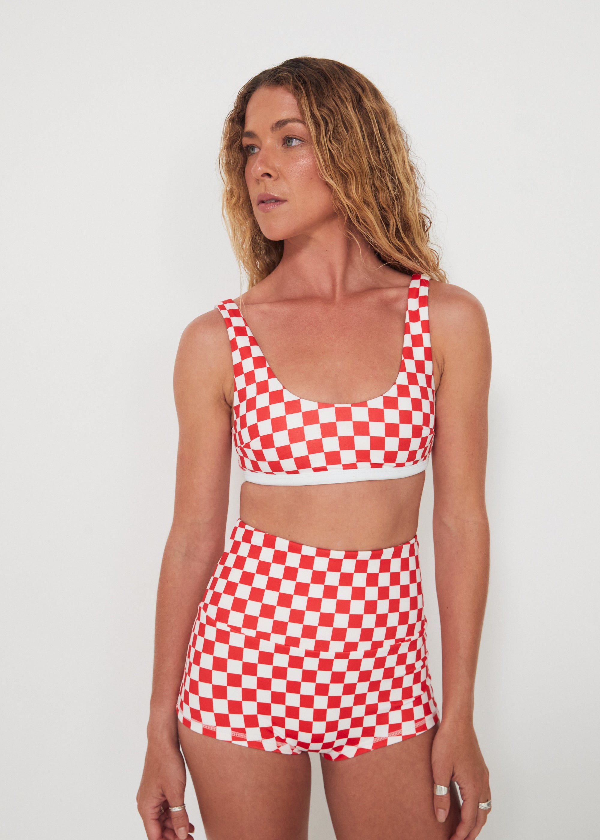 Woman wearing a red and white checkered two-piece swimsuit against a plain background