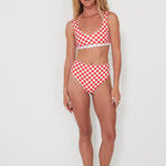 Woman wearing a red and white checkered bikini set on a white background