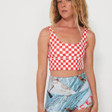 Woman wearing a red and white checkered punchy surf top and patterned ocean photographed shorts on a white background
