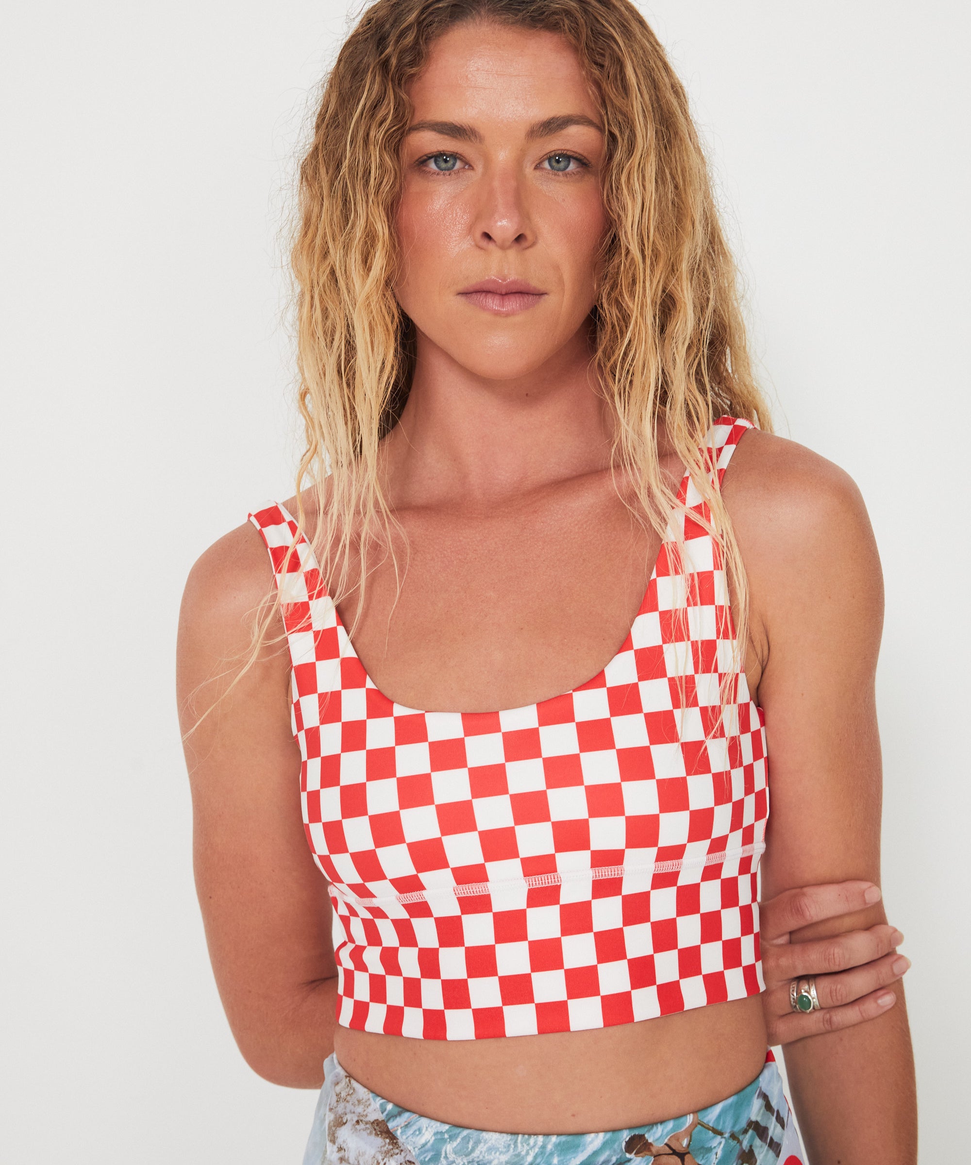Woman wearing a red and white checkered punchy surf crop top against a white background