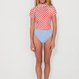 Person wearing a red and white checkered rashguard and light blue high-waisted bottoms on a white background