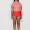 Person wearing a red and white checkered low rider rashugard top and red original betty bottoms shorts on a white background