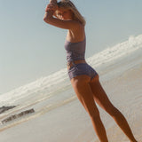 Woman in a striped swimsuit standing on a beach with clear sky