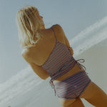 Woman in a striped swimsuit standing against a light background