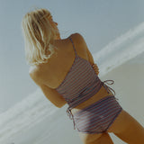 Woman in a striped swimsuit standing against a light background